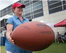  ??  ?? Ternnessee Titans controllin­g owner Amy Adams Strunk holds a fan’s giant football as she watches practice Tuesday at Saint Thomas Sports Park in Nashville.