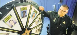  ?? MALCOLM DENEMARK Florida Today via AP ?? Brevard County Sheriff Wayne Ivey gets ready to spin his ‘Wheel of Fugitive’ in July 2017 in Titusville. A man says he lost a job because his picture was on the wheel even though he wasn’t a fugitive.