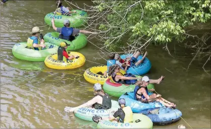  ?? / Steven Eckhoff ?? Inner tubers work to untangle from a fallen tree in the Etowah River during the Big Float on Saturday afternoon.