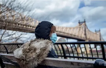  ??  ?? From left: A woman wearing a mask sits by a bridge in New York; a solitary Schnoodle dog on the highway outside Grant’s Tomb in Manhattan.