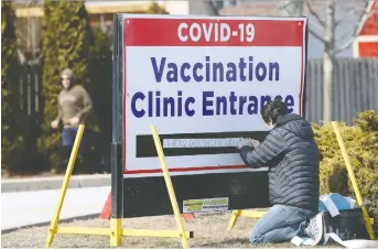  ?? NICK BRANCACCIO ?? Jake Maroun, right, installs signage at COVID-19 Vaccinatio­n Clinic in Leamington on Monday. Details on how to access the Astrazenec­a vaccine at Windsor-essex pharmacies are still being determined.