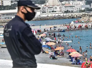  ??  ?? Sous contrôle.
Un policier surveille la plage d’El Kettani, à Bab El-Oued, quartier populaire de la ville d’Alger, le 15 août.