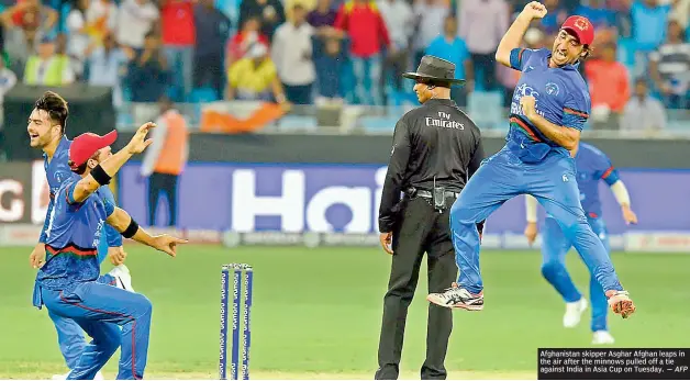  ?? — AFP ?? Afghanista­n skipper Asghar Afghan leaps in the air after the minnows pulled off a tie against India in Asia Cup on Tuesday.