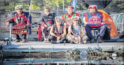  ?? CP PHOTO/HO-FACEBOOK-SWANSON OCCUPATION ?? Protesters gather at the Marine Harvest fish farm on Swanson Island, near Alert Bay, B.C. in a handout photo from the Facebook page Swanson Occupation. Ernest Alfred, 36, sitting cross-legged on the right wearing a cedar bark neck ring, sits with other...