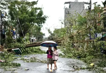  ??  ?? Women walk past uprooted trees in central Vietnam’s Quang Ngai province in the a ermath of Typhoon Molave.