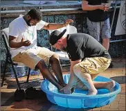  ?? MARSHALL GORBY / STAFF ?? Pastor Israel Baxter of New Hope Life Church and Pastor Joel Burton of Simple Street Ministry (right) wash each other’s feet at Courthouse Square.
