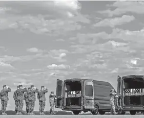  ?? ANDREW HARNIK/AP ?? A U.S. Marine Corps carry team salutes transfer cases containing the remains of, from left, Cpl. Jacob M. Moore, Gunnery Sgt. James W. Speedy, Capt. Ross A. Reynolds and Capt. Matthew J. Tomkiewicz of Allen, Ind., as they are loaded into transfer vehicles during a casualty return at Dover Air Force Base.