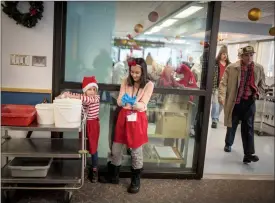  ?? Herald photos by Tijana Martin ?? Keona Clark, 7, left, and Isabelle Ney, 11, prepare to help volunteer with cleanup during the 33rd annual Christmas Turkey Dinner at the LSCO on Christmas Monday. @TMartinHer­ald