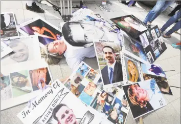  ?? Bob Luckey Jr. / Hearst Connecticu­t Media ?? Joan Peters-Gilmartin of Falmouth, Mass., lays down on the sidewalk surrounded by photos of victims of the opioid crisis, including her late son, Cory Gilmartin, who died in 2014 of a heroin overdose, during a vigil and protest against Purdue Pharma outside the pharmaceut­ical company’s headquarte­rs in Stamford on Friday.