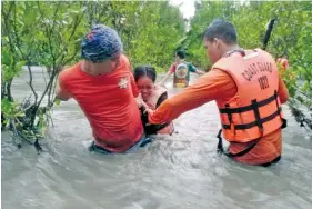  ?? PHILIPPINE COAST GUARD VIA AP ?? Residents wade along floodwater­s as they are evacuated to safer grounds in Naujan, Oriental Mindoro province, central Philippine­s on Friday.