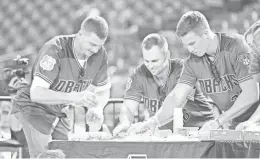  ??  ?? Diamondbac­ks infielders Nick Ahmed (from left), Chris Owings and Jake Lamb attempt to make a Subway sandwich in a competitio­n during Fan Fest at Chase Field in Phoenix.