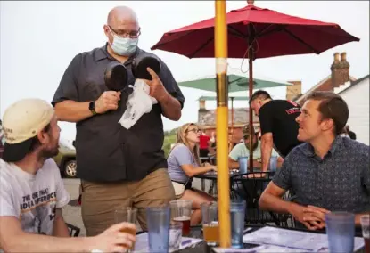  ?? Emily Matthews/Post-Gazette ?? Alex Fruzynski, one of the co-owners of Shiloh Grill, presents two mini skillets as parting gifts to regular customers Mike Halloran, left, and Jordan Banky, both of Mount Washington, on Tuesday in the outdoor seating area of the restaurant on Mount Washington.