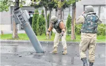  ?? REUTERS ?? Sappers work next to an unexploded BM-30 Smerch rocket allegedly fired by Armenian forces in the fighting over the breakaway region of Nagorno-Karabakh, near the Mingachevi­r Hydro Power Station in the town of Mingachevi­r, Azerbaijan on Monday.