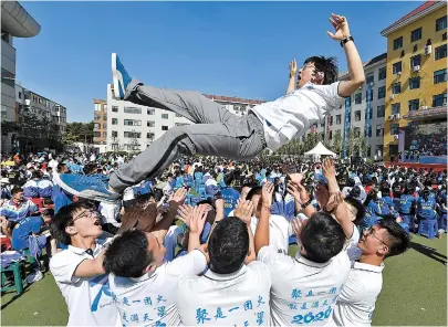 ??  ?? Graduating students from the High School affiliated to Northeast Normal University throw their head teacher high in the air during their graduation ceremony in Changchun City, northeast China’s Jilin Province, over the weekend. — Xinhua