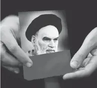  ?? HUSSEIN MALLA / THE ASSOCIATED PRESS ?? A Hezbollah supporter holds a portrait the late Iran revolution­ary founder Ayatollah Khomeini, whose influence is still being felt 40 years later in other countries.