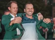  ?? CHRIS CARLSON/THE ASSOCIATED PRESS ?? Sergio Garcia, who had been 0-for-73 in majors, dons green jacket with help from Danny Willett.