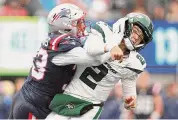  ?? Elsa/Getty Images ?? Jets quarterbac­k Zach Wilson is hit by the Patriots’ Anfernee Jennings on Sunday in East Rutherford, N.J.