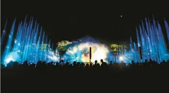  ?? JOE BURBANK/ORLANDO SENTINEL ?? Universal Studios visitors take in scenes from “Cinematic Celebratio­n” in July 2018. The show employed imagery of films projected onto dancing fountains and flanked by fireworks.