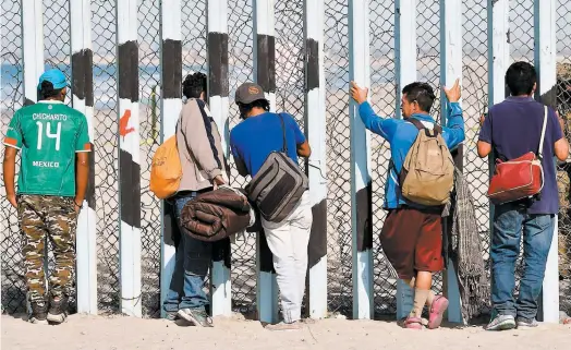  ?? PHOTO AFP ?? Des migrants honduriens se sont arrêtés, hier, sur une plage de Tijuana, devant la clôture séparant le Mexique des États-unis.