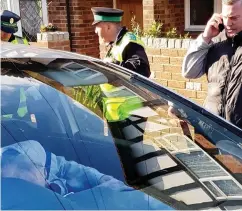  ??  ?? Locked in: Wardens stand by the car with the man inside