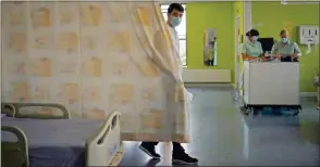  ??  ?? USA TODAY Stroke therapy worker Cavan Smith pulls the curtains around a patient’s bed on the Acute Stroke Unit at the Royal Blackburn Teaching Hospital in Blackburn, northwest England, as National Health Service staff in Britain fight the novel coronaviru­s COVID-19 pandemic.