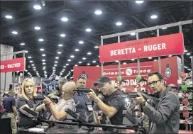  ?? NEW YORK TIMES 2016 ?? People check out weapons at an NRA convention last year. The NRA and the ACLU were among the groups that objected to using Social Security Administra­tion data to prevent gun sales to people with disabling mental illness.