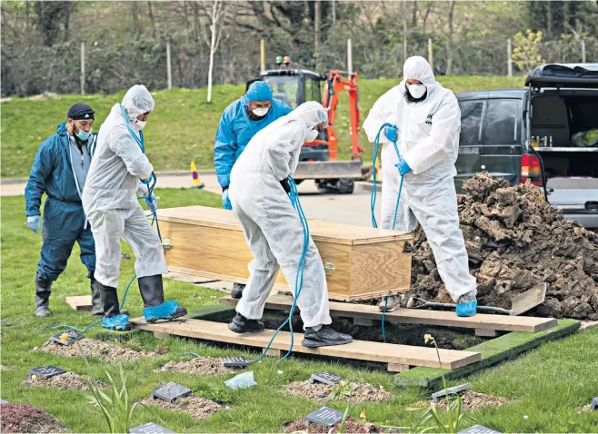  ?? ?? Men wearing protective suits lower Ismail Abdulwahab’s coffin into the ground at the Eternal Gardens Muslim burial ground in Chislehurs­t, south-east London, on April 3 2020