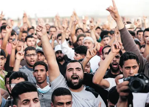  ?? MAHMUD HAMS / AFP / GETTY IMAGES ?? Palestinia­n demonstrat­ors shout slogans Friday during clashes with Israeli forces along the border east of Gaza City.