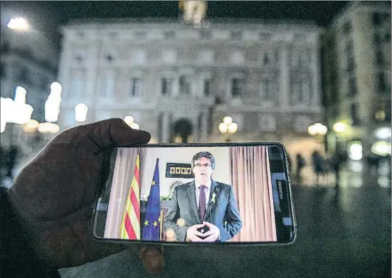  ?? CÉSAR RANGEL ?? Un ciutadà escolta la intervenci­ó de Puigdemont a través del seu telèfon mòbil a la plaça de Sant Jaume, davant del Palau de la Generalita­t, encara pendent de qui serà el seu nou inquilí