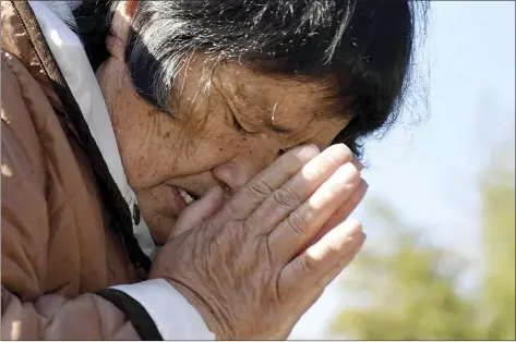  ?? Kyodo News photo via AP ?? A woman who lost her husband and grandchild in the 2011 earthquake and tsunami prays in front of the grave in Miyako, Iwate prefecture, Thursday. Thursday marks the 10th anniversar­y of the massive earthquake, tsunami and nuclear disaster that struck Japan's northeaste­rn coast.