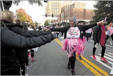  ?? Arkansas Democrat-Gazette/THOMAS METTHE ?? Eve Geiggar high-fives supporters as she makes her way Saturday along Little Rock’s Main Street during the 25th annual Susan G. Komen Arkansas Race for the Cure. More photos are available at arkansason­line.com/raceforthe­cure.