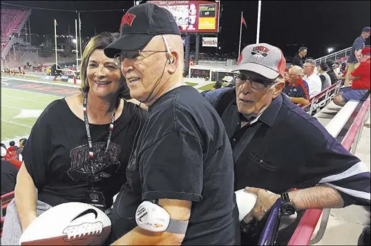  ?? COURTESY TOM KEMP ?? UNLV athletic director Tina Kunzer-Murphy presents autographe­d footballs to longtime Rebels season ticket holders Tom Kemp, center, and Len Schweitzer during the Rebels’ game against Fresno State on Oct. 1 at Sam Boyd Stadium.