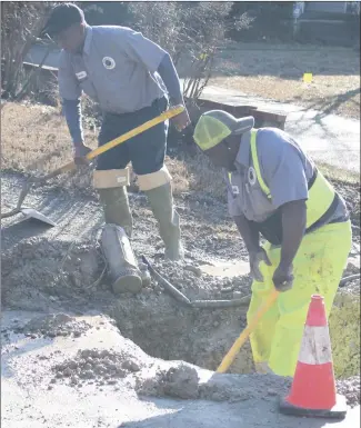  ?? Brodie Johnson • Times-Herald ?? The Forrest City Water Department works to repair a main line on Izard Street this morning. Charlie Clayborn, left, and Mike Davis, with the water department, use shovels and a pump to empty the hole in order to clear access to the damaged water line.