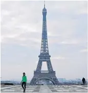  ?? THIBAULT CAMUS/AP ?? People walk past the Eiffel Tower on March 18 in Paris. It’s still possible to enjoy a virtual visit to the City of Lights thanks to earthcam.com.
