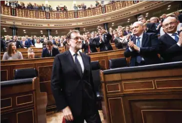  ?? DANIEL OCHOA DE OLZA/AFP ?? Mariano Rajoy (centre) is applauded after being re-elected during the parliament­ary investitur­e vote for a prime minister, at the Spanish Congress on Saturday in Madrid.