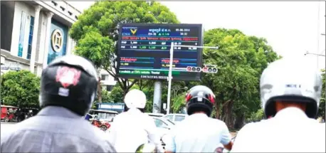  ?? HENG CHIVOAN ?? Motorists stare at a CSX billboard at a traffic stop along Monivong Boulevard in Daun Penh district’s Wat Phnom commune in the capital.