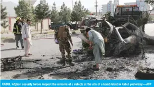  ?? —AFP ?? KABUL: Afghan security forces inspect the remains of a vehicle at the site of a bomb blast in Kabul yesterday.