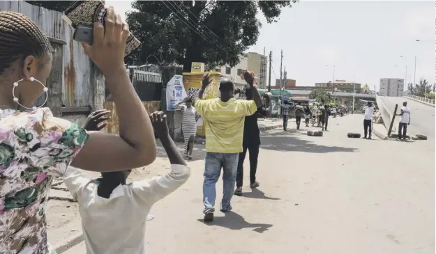  ??  ?? 0 People walk with their hands above their heads as they pass security checkpoint­s manned by security forces holding machetes in Lagos