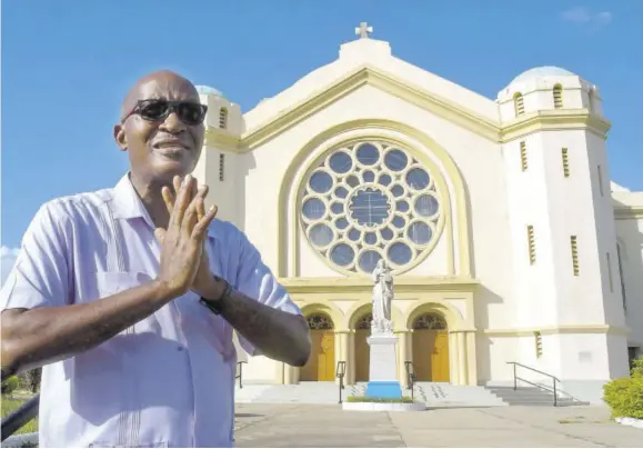  ??  ?? Rector for the cathedral Fr Kingsley Asphall speaks about the ministry of the 110-year-old cathedral (in background) on North Street in the community.