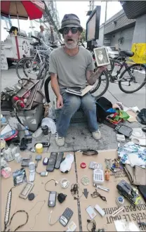  ?? ARLEN REDEKOP/ PNG ?? Russ Staniforth, holding a photograph of his grandfathe­r, lays out his wares by the Commercial- Broadway SkyTrain station daily, hoping to earn enough to support himself and his drug habit.