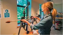  ??  ?? Michelle Bebber, a PhD archeology student at Kent State University, loads a bow with a recreated ancient arrow in Kent, Ohio. — AP photos