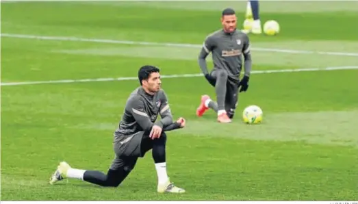  ?? J.J. GUILLÉN / EFE ?? Luis Suárez realiza estiramien­tos en el entrenamie­nto del Atlético de Madrid con Lodi al fondo.