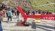  ??  ?? People look at the damaged tail end of a private helicopter which was hit by an object while making an emergency landing at Kedarnath helipad soon after take-off, in Rudrapraya­g district, Monday