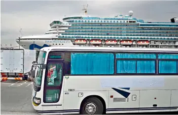  ?? — AFP ?? A bus with a driver wearing protective gear departs from the dockside next to the Diamond Princess cruise ship at the Daikoku Pier Cruise Terminal in Yokohama port on Friday.