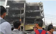  ?? (AFP) ?? Onlookers gather outside a burned down commercial building a day after a fire broke out, in New Delhi on Saturday