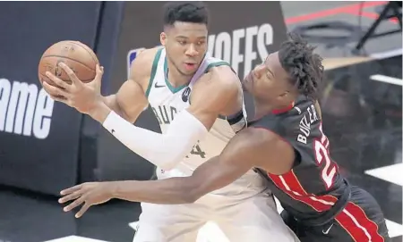  ?? JOHN MCCALL/SUN SENTINEL ?? The Heat’s opener at FTX Arena is a reminder of what was in last season’s playoffs for Jimmy Butler, right, and Giannis Antetokoun­mpo.