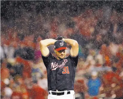  ?? PATRICK SEMANSKY/ASSOCIATED PRESS ?? Washington Nationals pitcher Max Scherzer winds up during a rainy sixth inning Monday night. Scherzer allowed one run in seven strong innings to help the Nationals defeat the Los Angeles Dodgers and force a fifth game in their NL Division Series.