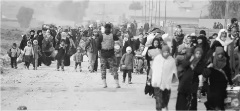  ??  ?? Displaced Iraqi civilians, who fled the Islamic State stronghold of Mosul, walk with children in the Intisar district of eastern Mosul, Iraq. — Reuters photo