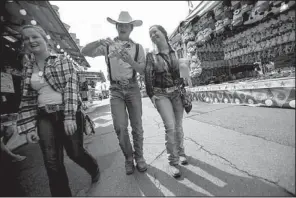  ?? Arkansas Democrat-Gazette/MELISSA SUE GERRITS ?? Amber Staley, 17 (from left), Michael Stanley, 15, and Madison Evans, 16, all of Cabot, walk through the Midway at the Arkansas State Fair on Saturday afternoon. The three were taking a lunch break before heading back to show their miniature rex rabbits.