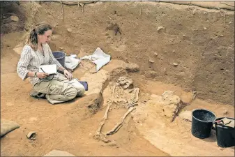  ?? [TSAFRIR ABAYOV/THE ASSOCIATED PRESS] ?? An archaeolog­ist takes notes at an ancient Philistine burial ground near Ashkelon, Israel. Human remains yielded bits of DNA that researcher­s say helps prove the geographic origin of the nemeses of the biblical Israelites.